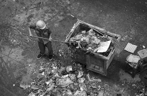 Construction workers loading a builders skip with debris